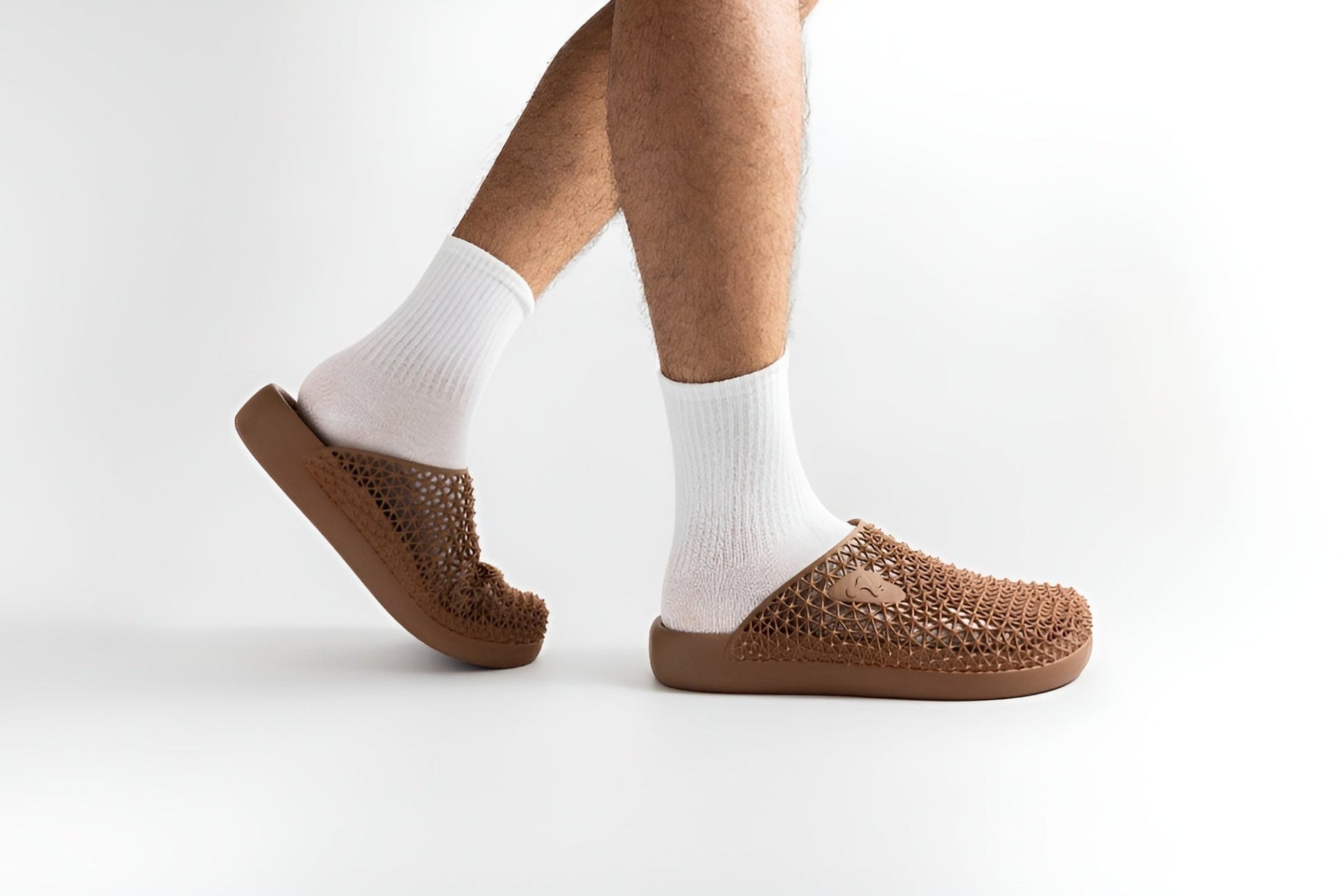 Brown slippers worn with white socks on a light gray background