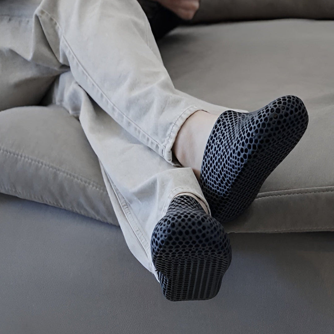 Person sitting on a couch wearing socks with textured sole design.