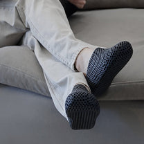 Person sitting on a couch wearing socks with textured sole design.